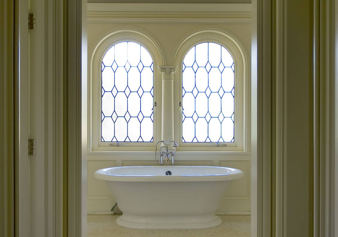 The master bathroom features leaded glass arched windows.